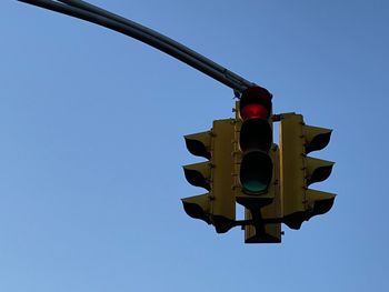 Low angle view of red stop light road signal against clear blue sky in mount vernon new york 