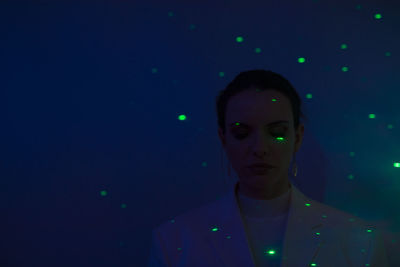 Close-up of young woman against illuminated background