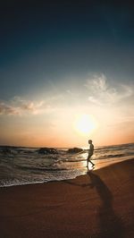 Silhouette man fishing in sea against sky during sunset