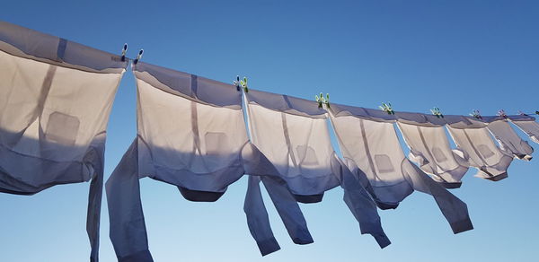 Low angle view of clothes drying against blue sky