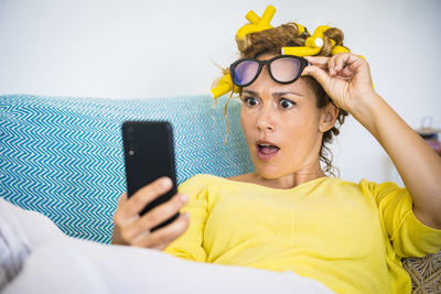 Close-up of woman holding smart phone sitting on sofa at home