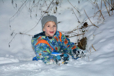 Portrait of smiling boy playing on snow covered field during winter