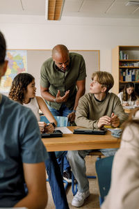Male professor teaching to teenage girl and boy in classroom