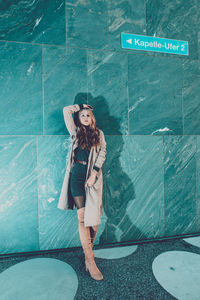 Portrait of young woman standing against wall