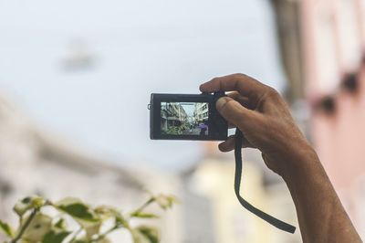 Cropped image of man photographing in city through digital camera