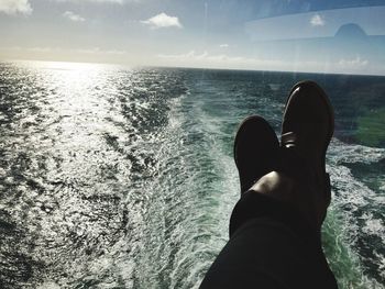 Low section of man in sea against sky