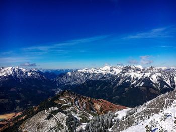 Scenic view of snowcapped mountains against blue sky