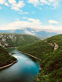 Scenic view of river amidst green landscape against sky