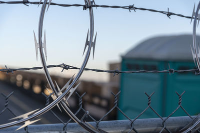 Close-up of barbed wire fence against sky