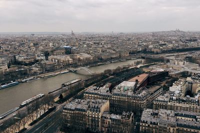 Aerial view of river running through city against cloudy sky