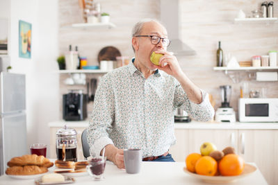 Senior man eating fruits at kitchen