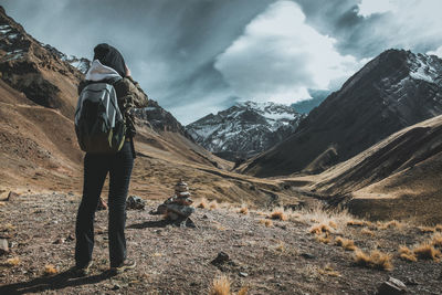 Rear view of woman hiking on field against sky