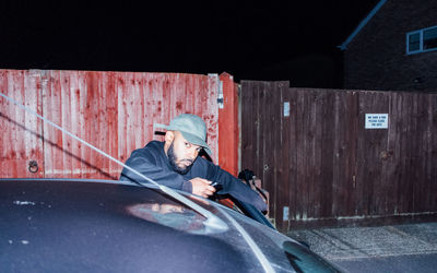 Portrait of man standing by car at night