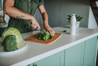 Woman cutting vegetables at kitchen counter