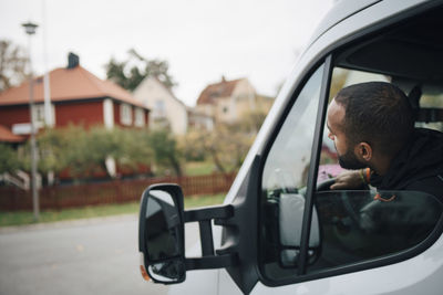 Male worker sitting in delivery van at city