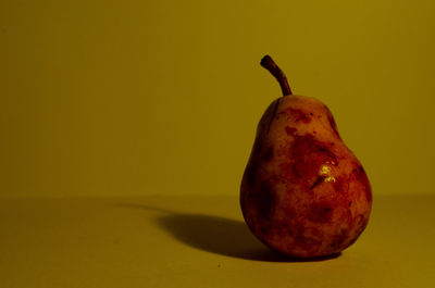 Close-up of apple on table against yellow background