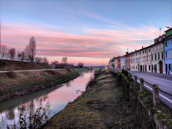 Canal amidst buildings against sky during sunset