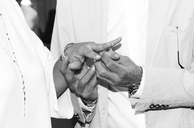 Midsection of man putting ring on finger of bride during wedding ceremony