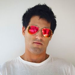 Portrait of young man wearing sunglasses against white background