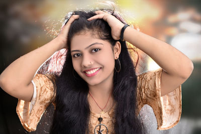 Portrait of smiling teenage girl with hand in hair