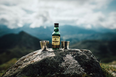 Close-up of beer on rock against sky