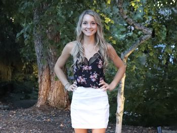 Portrait of smiling young woman standing against trees