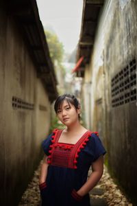 Portrait of woman standing against building