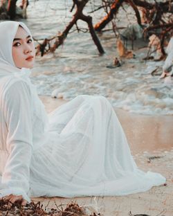 Side view of young woman sitting on tree