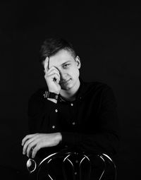Portrait of young man using smart phone against black background