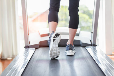 Low section of woman walking on treadmill