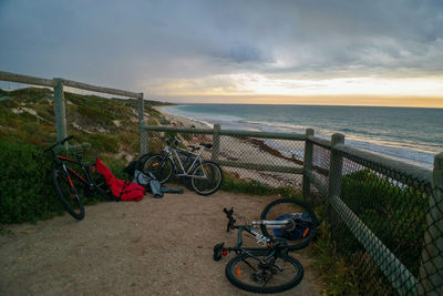 Bicycle on beach against sky during sunset
