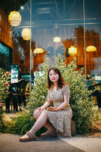 Portrait of young woman sitting on street