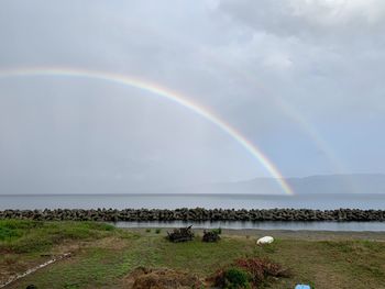 Scenic view of rainbow over sea against sky