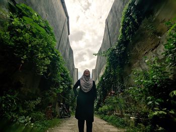 Low angle view of wearing hijab while standing on footpath amidst plants