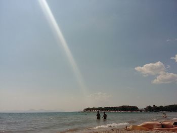 People at beach against sky