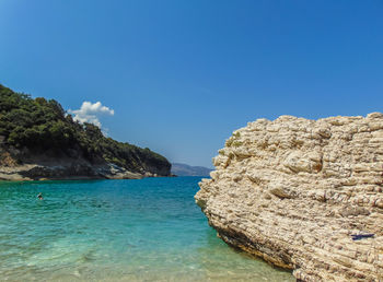 Rock formations in sea against clear blue sky