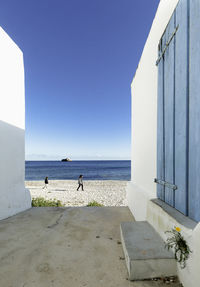 People on beach against clear blue sky