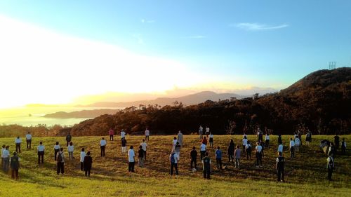 People on field against sky during sunset