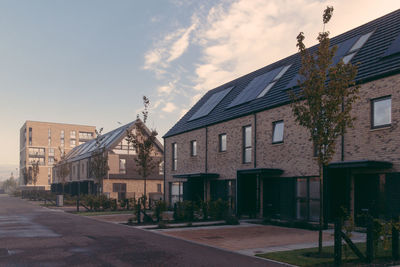 Residential buildings by street against sky