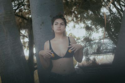 Portrait of young woman standing by tree