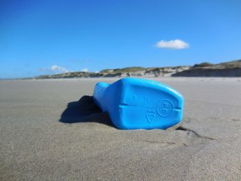 Blue container on beach against sky