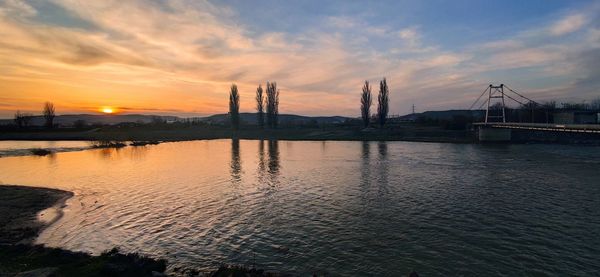 Bridge over river against sky during sunset