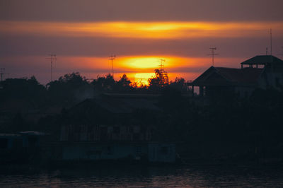 Silhouette houses against sky during sunset