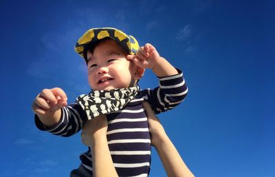 Low angle view of boy against blue sky