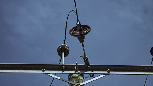 Low angle view of electric lamp hanging against sky