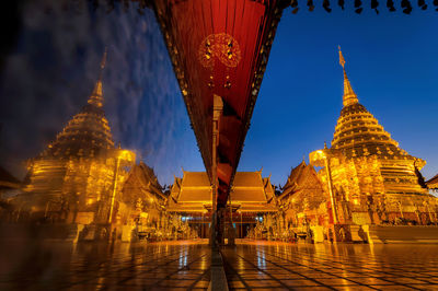 Illuminated buildings in temple against sky