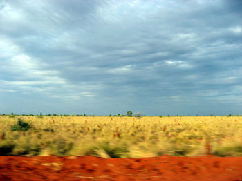 Scenic view of field against cloudy sky