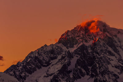 Scenic view of snowcapped mountains against orange sky