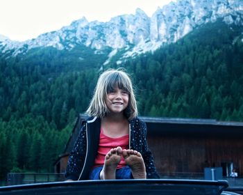 Portrait of smiling young woman sitting on mountain