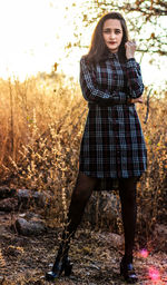 Portrait of young woman standing against tree